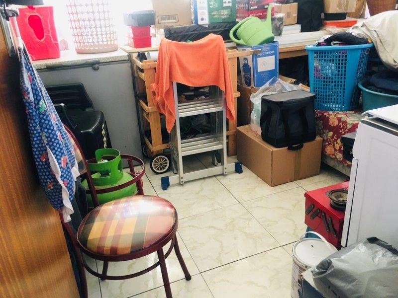 A utility space featuring tiled flooring, currently used for storage with various household items present.
