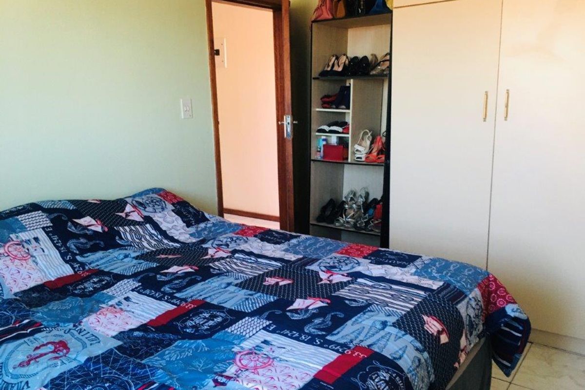 A bedroom featuring built-in wardrobe storage, tiled flooring, and direct access to an adjoining room.