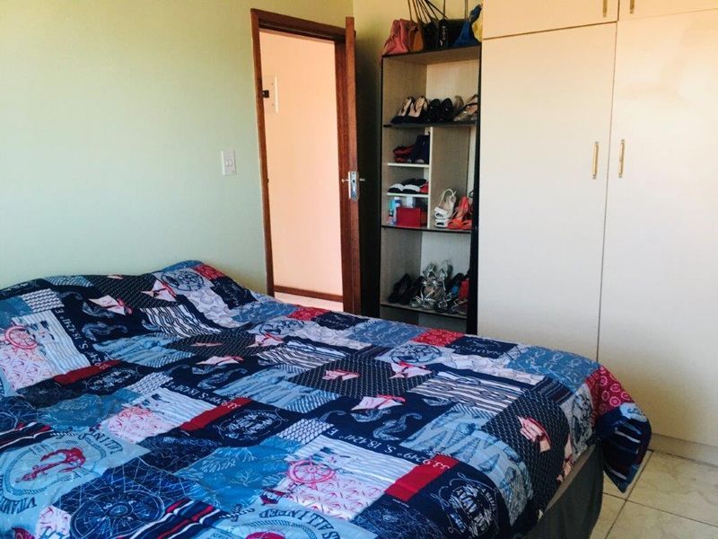 A bedroom featuring built-in wardrobe storage, tiled flooring, and direct access to an adjoining room.