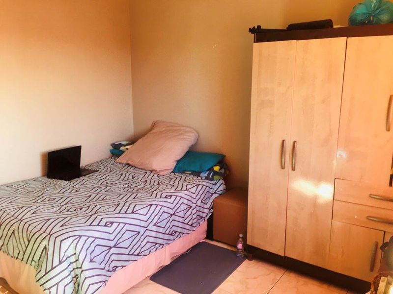 A standard bedroom featuring tiled flooring and neutral wall finishes, providing a functional space for rest.