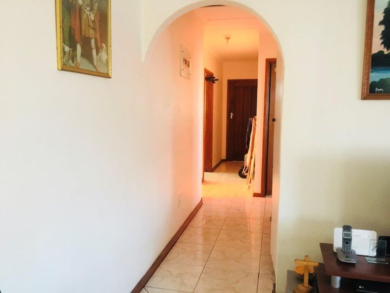 A bright hallway featuring tiled flooring and an arched entryway leading to internal rooms with timber doors.