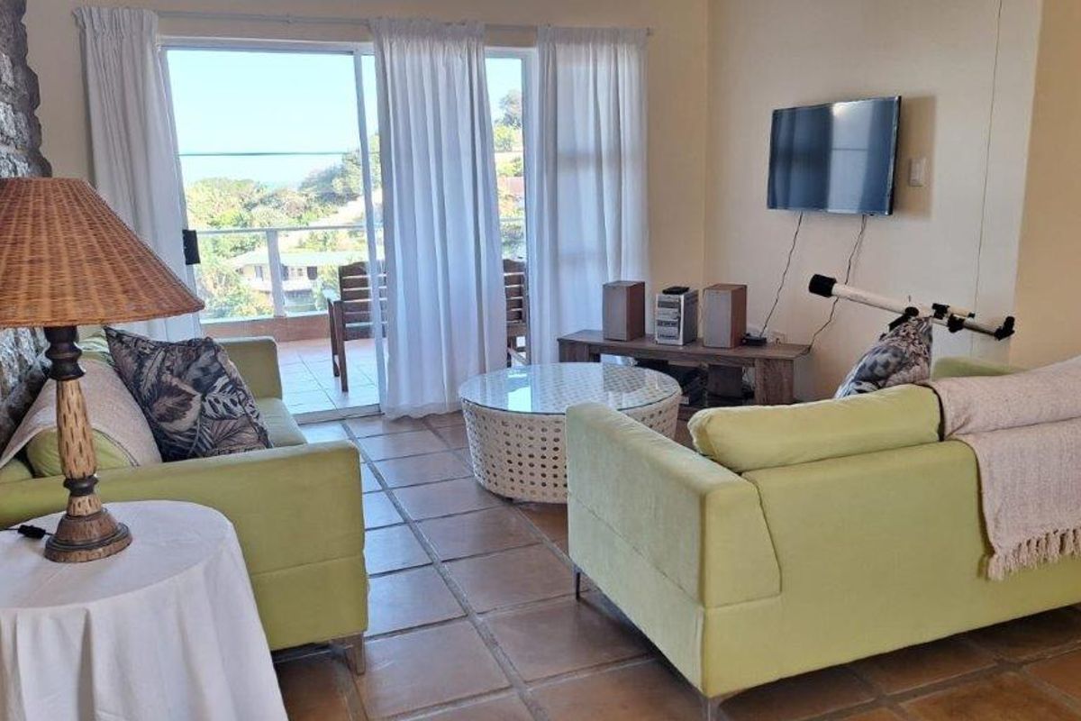 A comfortable living room featuring a textured stone accent wall, tiled flooring, and direct access to an outdoor balcony through sliding glass doors.