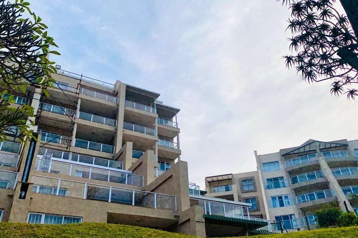 Low angle view of a multi-story apartment complex featuring tiered balconies with glass balustrades and ongoing exterior maintenance.