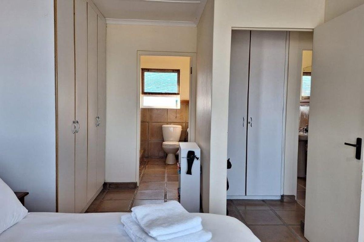 Bedroom featuring built-in cupboards and an adjoining en-suite bathroom with tiled flooring throughout.