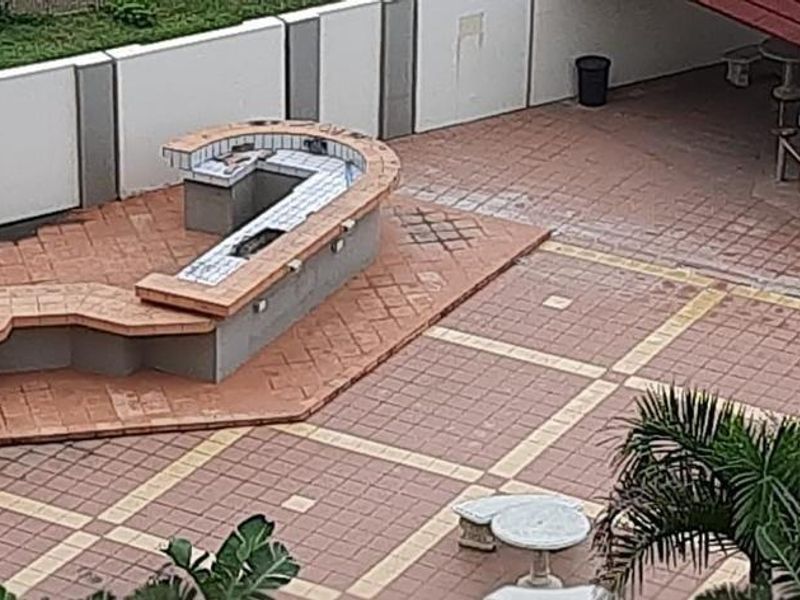 Outdoor patio area featuring a built-in braai station and a covered bar area, finished with tiled flooring and perimeter walling.