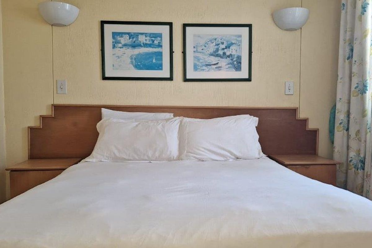 A bedroom featuring a built-in wooden headboard with integrated bedside tables and wall-mounted lighting fixtures.