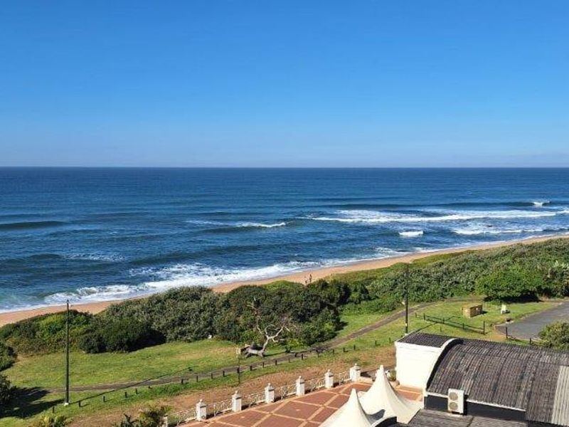 A scenic elevated view overlooking the coastline, beach, and ocean, showcasing the property's prime location.