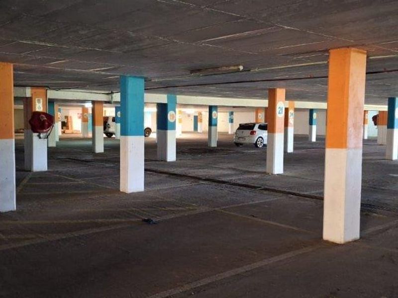 A large, open-plan underground parking garage featuring concrete flooring, structural support columns, and designated parking bays.