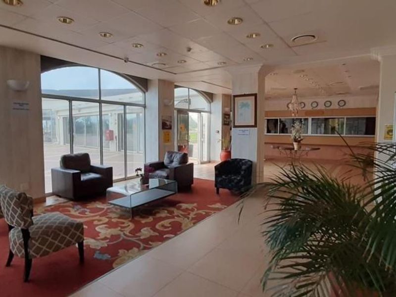 Spacious apartment building entrance lobby featuring a reception area, large glass sliding doors, and tiled flooring.