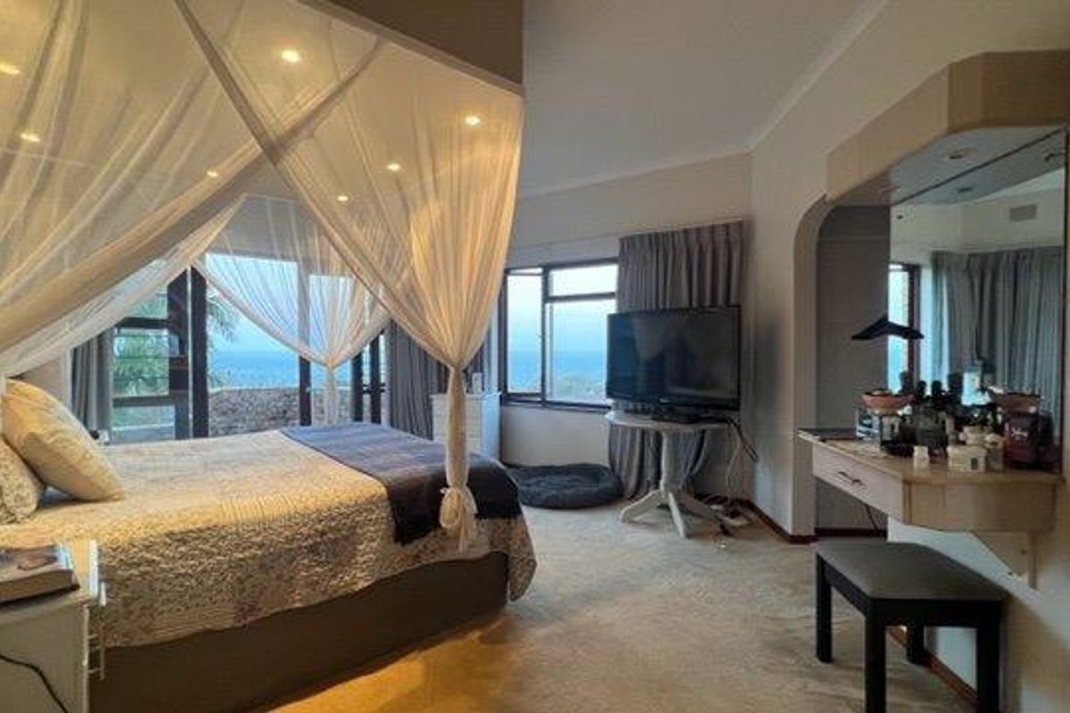 Spacious bedroom featuring a built-in vanity, recessed lighting, and large windows with sliding doors offering scenic views.