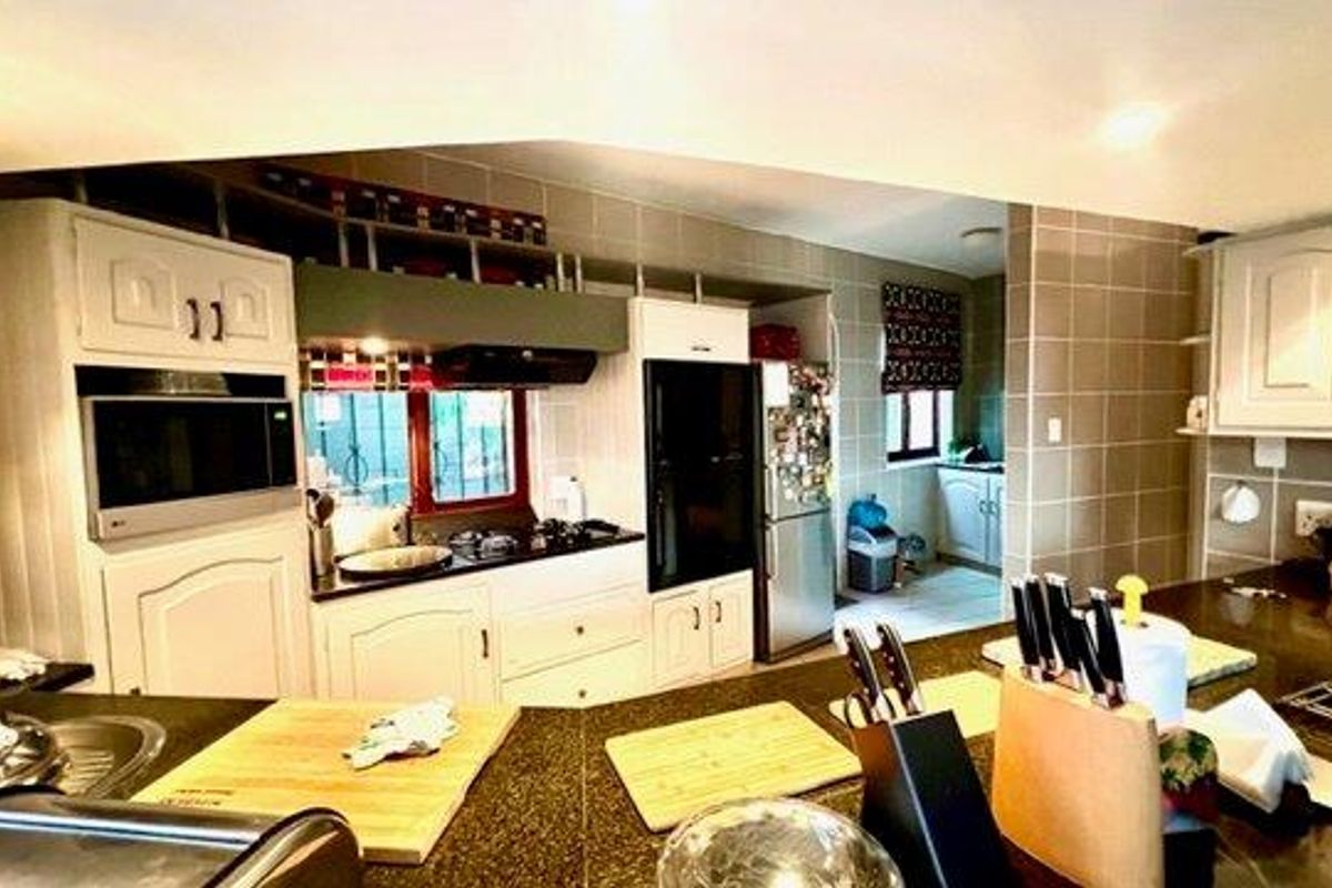 A functional kitchen featuring granite countertops, built-in oven, gas hob, extractor fan, and ample fitted cabinetry with a tiled backsplash.