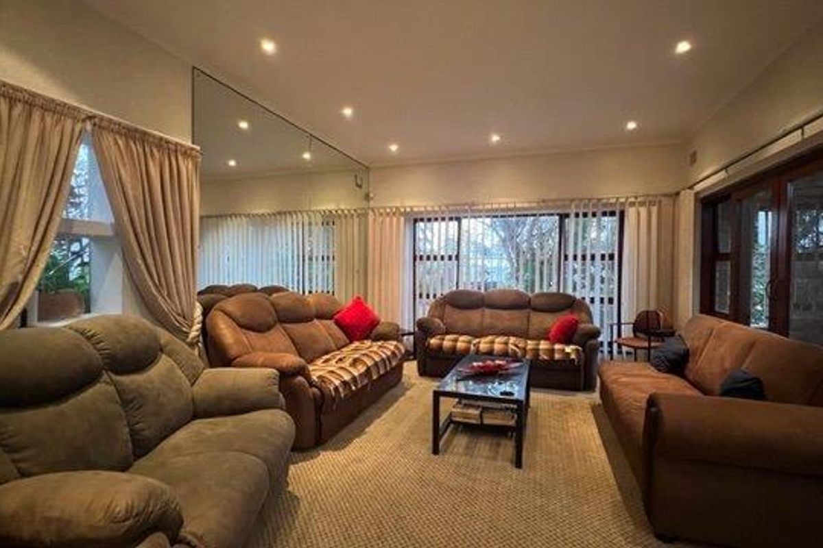 Spacious living room featuring recessed downlighting, a large feature mirror, and sliding glass doors providing access to the exterior.