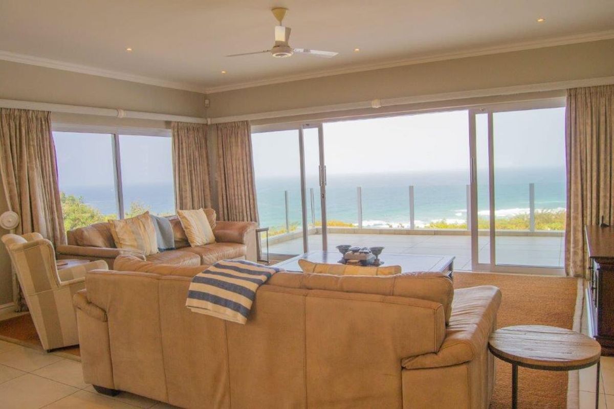 Spacious living room featuring large sliding glass doors that open to a balcony with expansive ocean views and tiled flooring throughout.