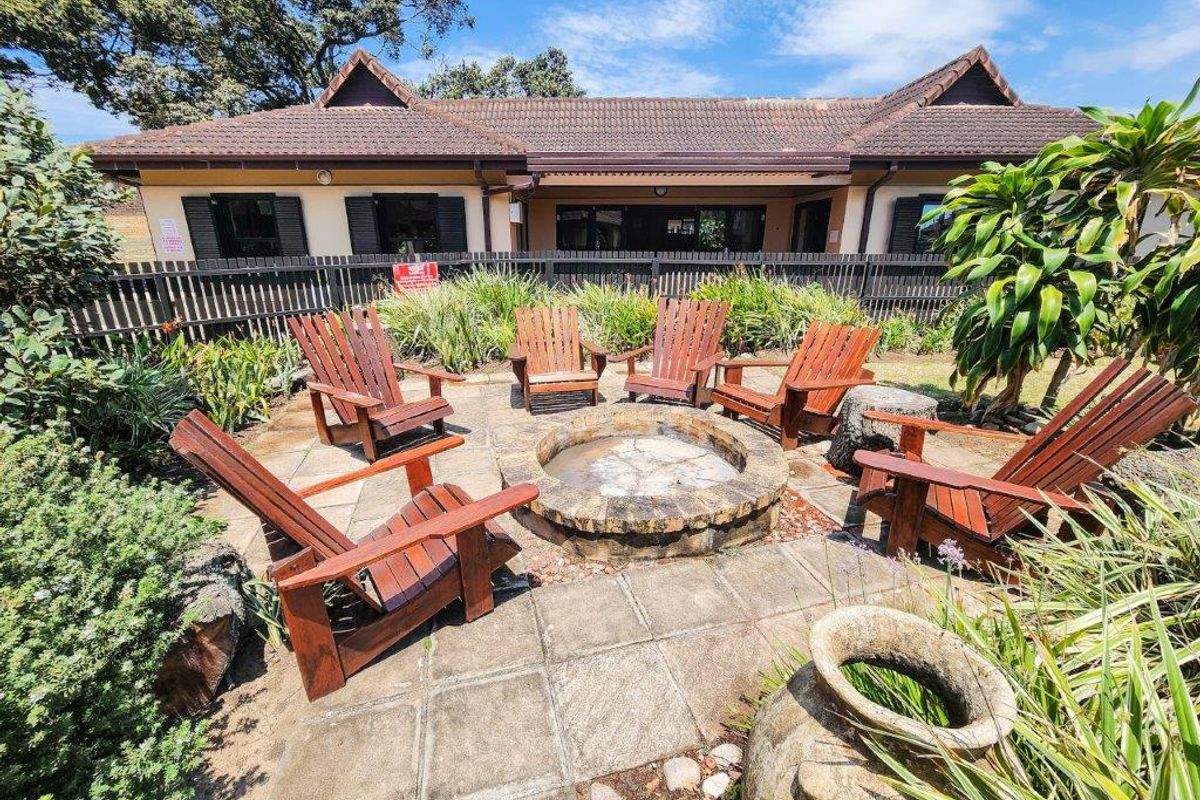 Outdoor entertainment area featuring a stone-built fire pit and paved patio space, set within a landscaped garden area.