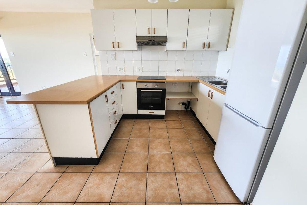 Functional kitchen featuring white cabinetry, tiled backsplash, built-in oven, hob, extractor fan, and tiled flooring, with an open-plan layout.