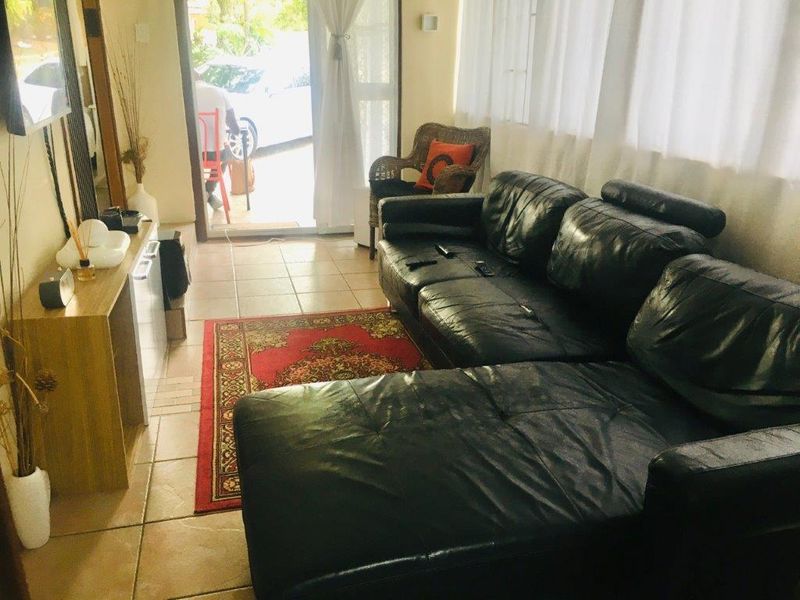 A living room area featuring tiled flooring and a sliding glass door providing access to the exterior.