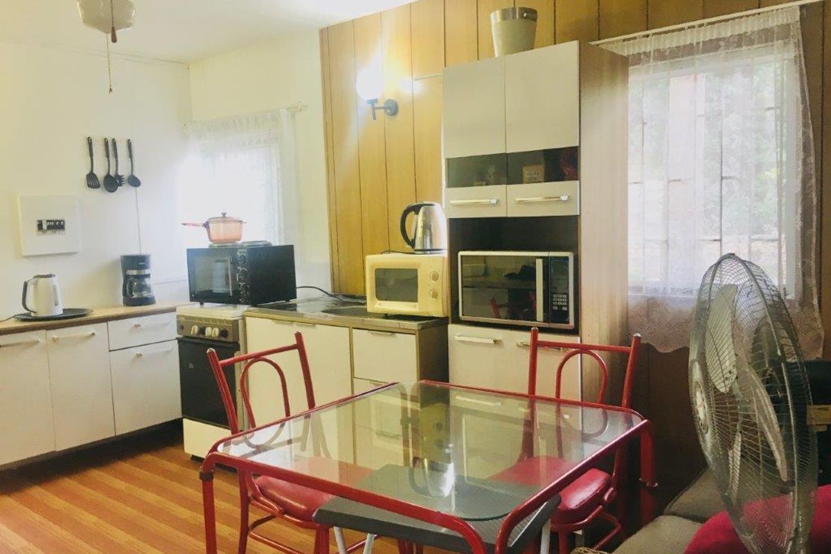 A dated kitchen featuring wood paneling, white cabinetry, and laminate flooring, offering significant potential for a modern renovation and aesthetic update.