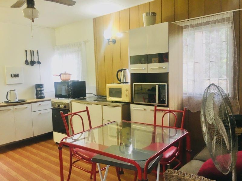A dated kitchen featuring wood paneling, white cabinetry, and laminate flooring, offering significant potential for a modern renovation and aesthetic update.