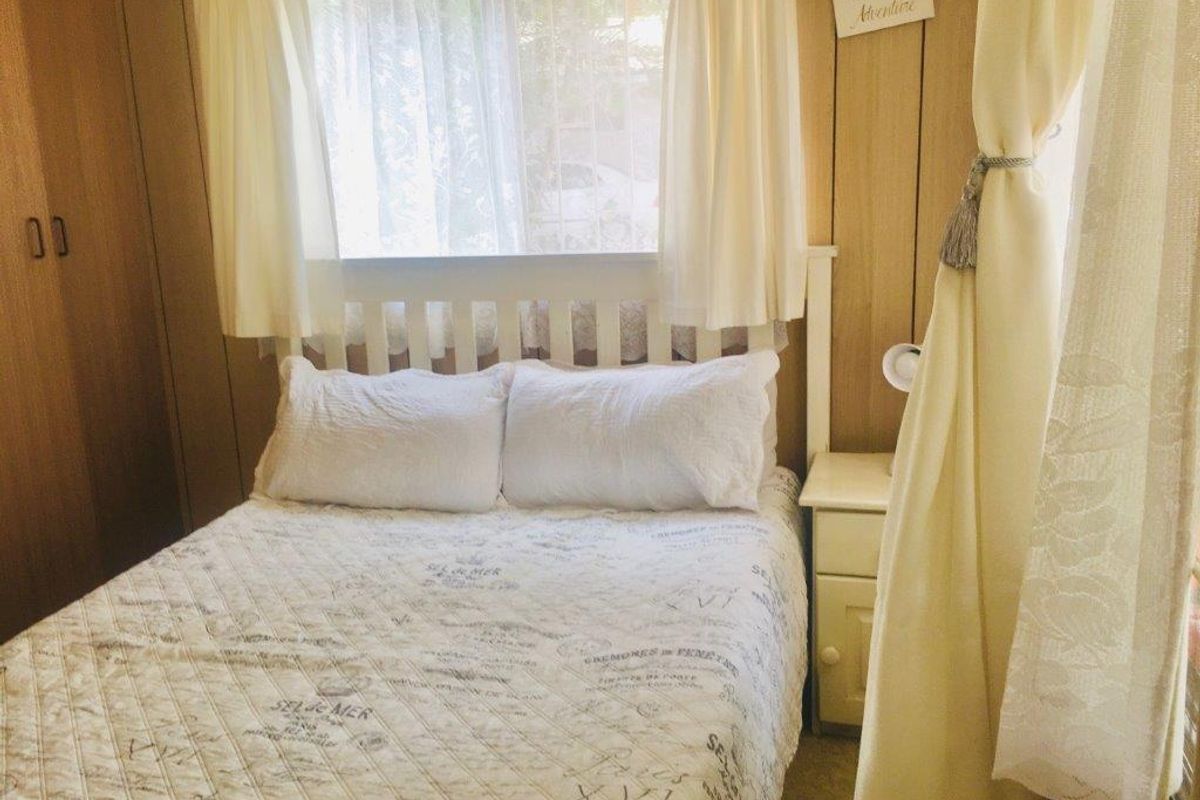 A cozy bedroom featuring timber wall paneling and a built-in wardrobe, offering a functional and traditional living space.