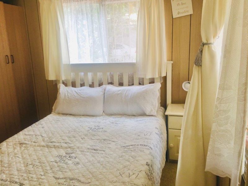 A cozy bedroom featuring timber wall paneling and a built-in wardrobe, offering a functional and traditional living space.