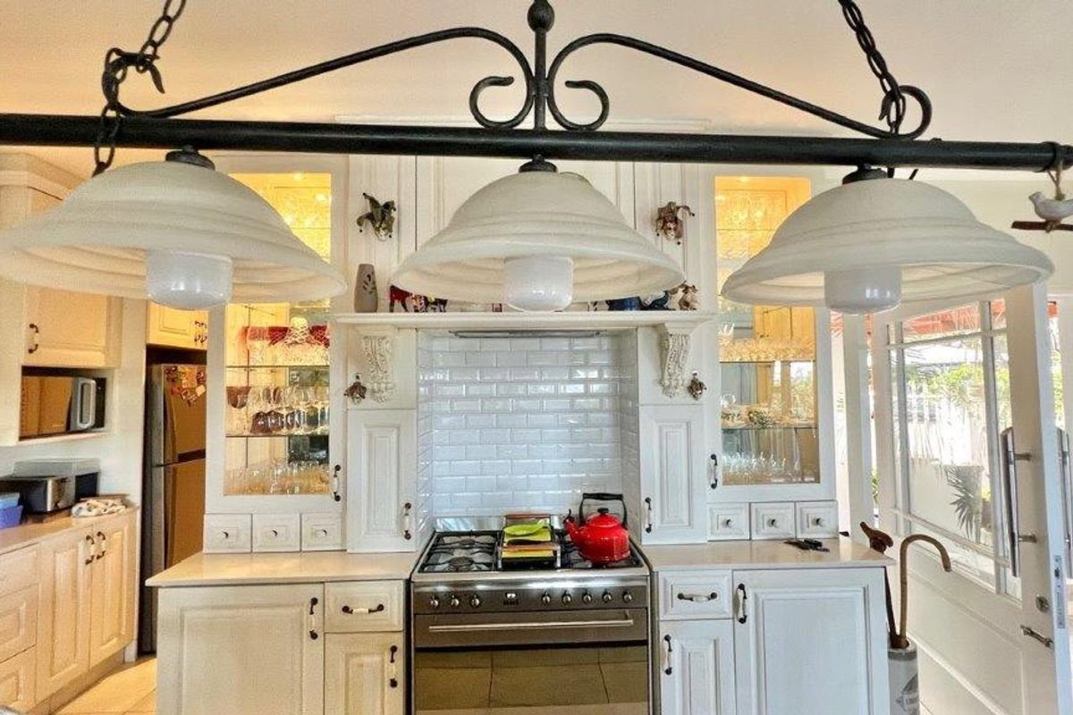 A well-appointed kitchen featuring classic white cabinetry, a subway tile backsplash, a gas stove with oven, and elegant glass-front display cabinets.