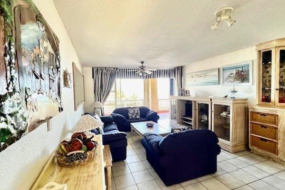 Spacious living room featuring tiled flooring, a ceiling fan, and large sliding glass doors that provide access to an outdoor balcony area.