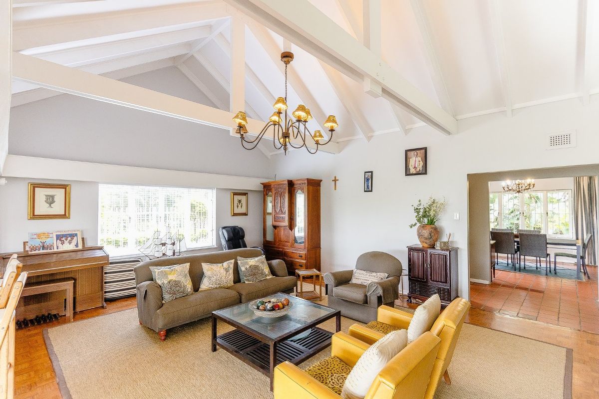 Spacious living room featuring a high vaulted ceiling with exposed timber beams and a mix of parquet and terracotta tile flooring.