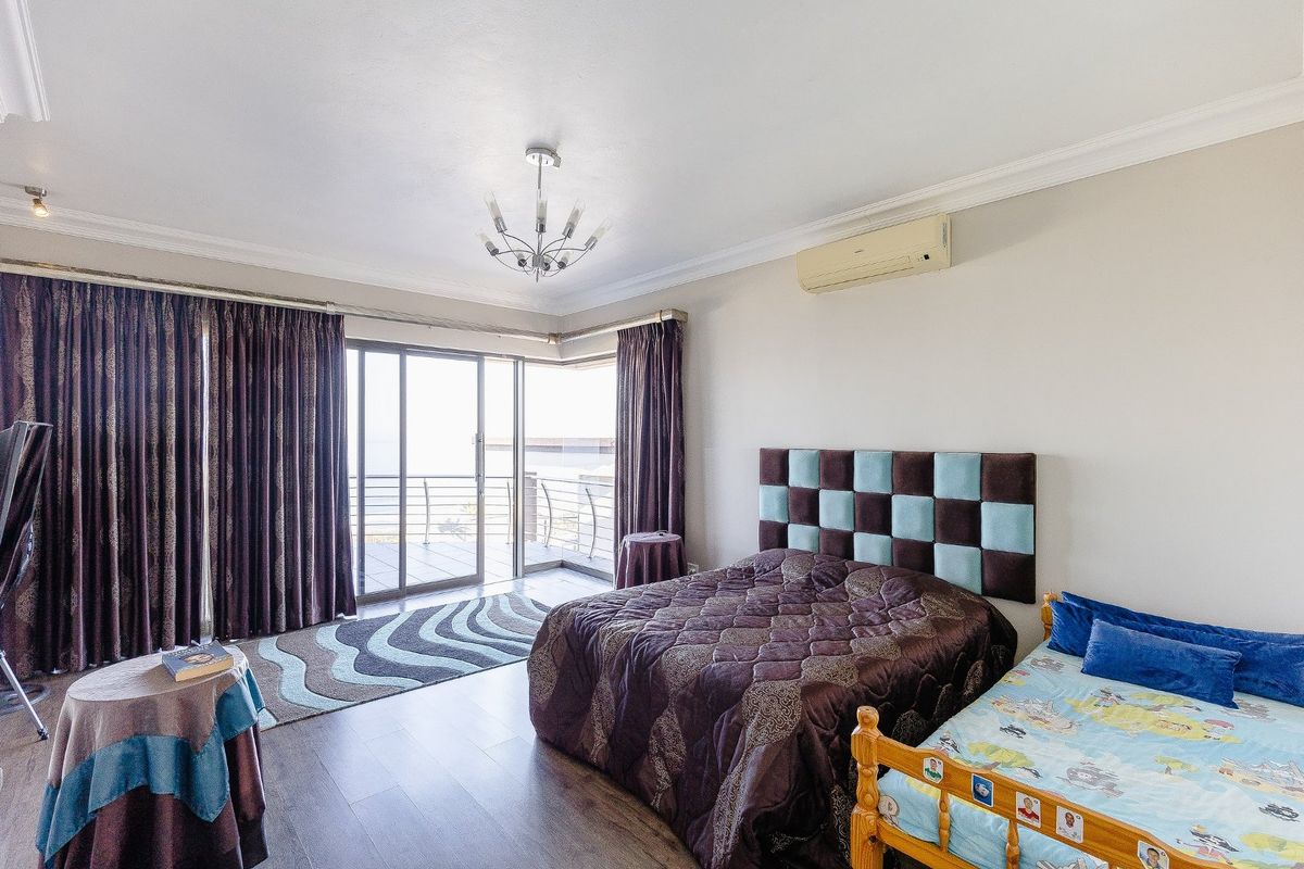 Spacious bedroom featuring laminate flooring, crown molding, an air conditioning unit, and large sliding glass doors leading to an outdoor balcony.