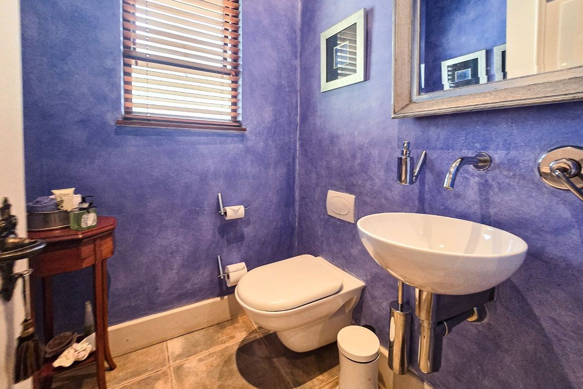 A compact guest bathroom featuring a wall-mounted toilet, modern basin with wall-mounted faucet, and distinctive blue textured wall finishes.