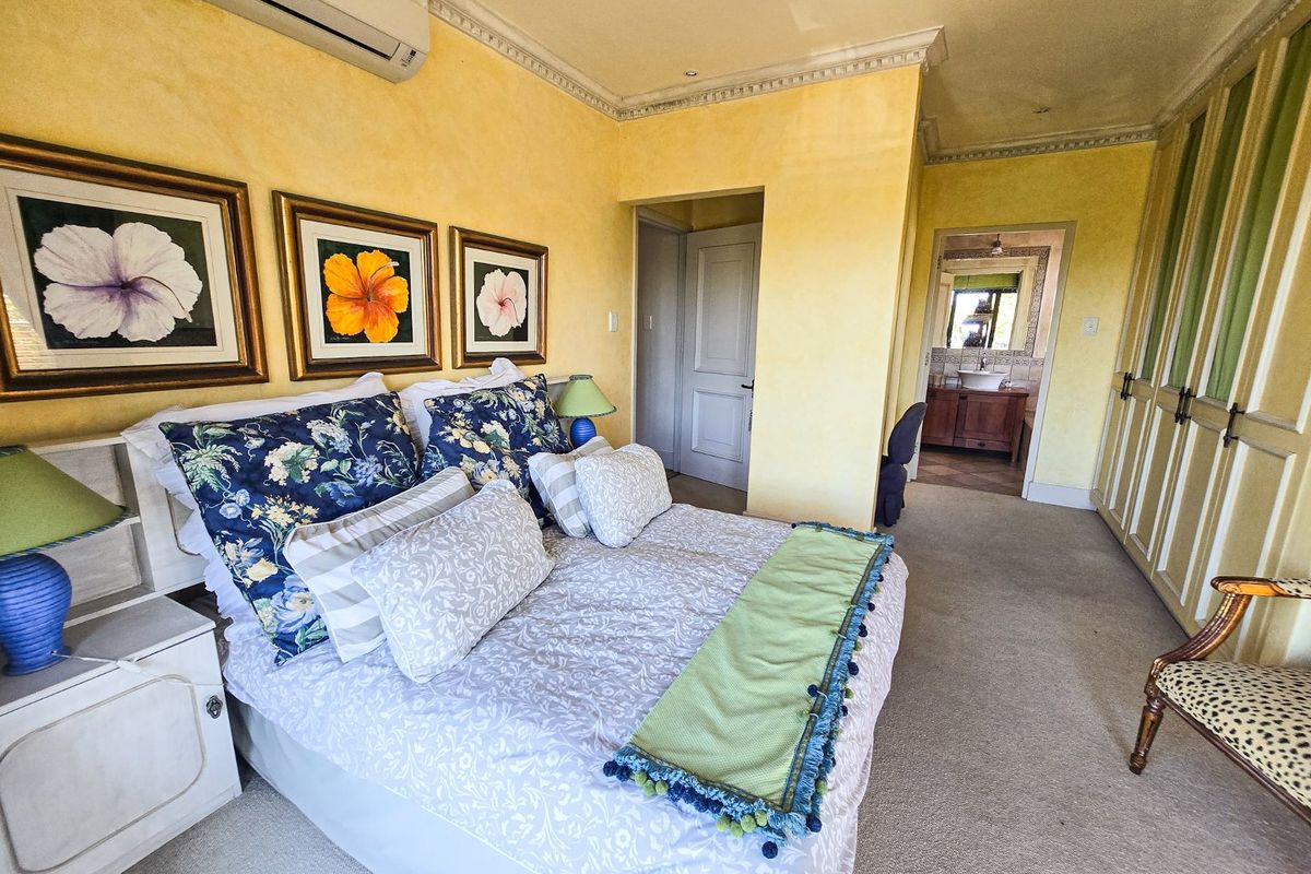 Spacious bedroom featuring built-in cupboards, crown molding, and an en-suite bathroom, finished with a split-system air conditioner for climate control.