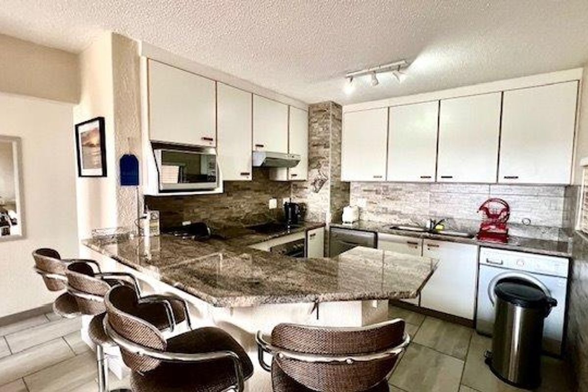 A functional kitchen featuring granite countertops, stone tile backsplash, built-in cabinetry, and integrated appliances including a dishwasher and washing machine.