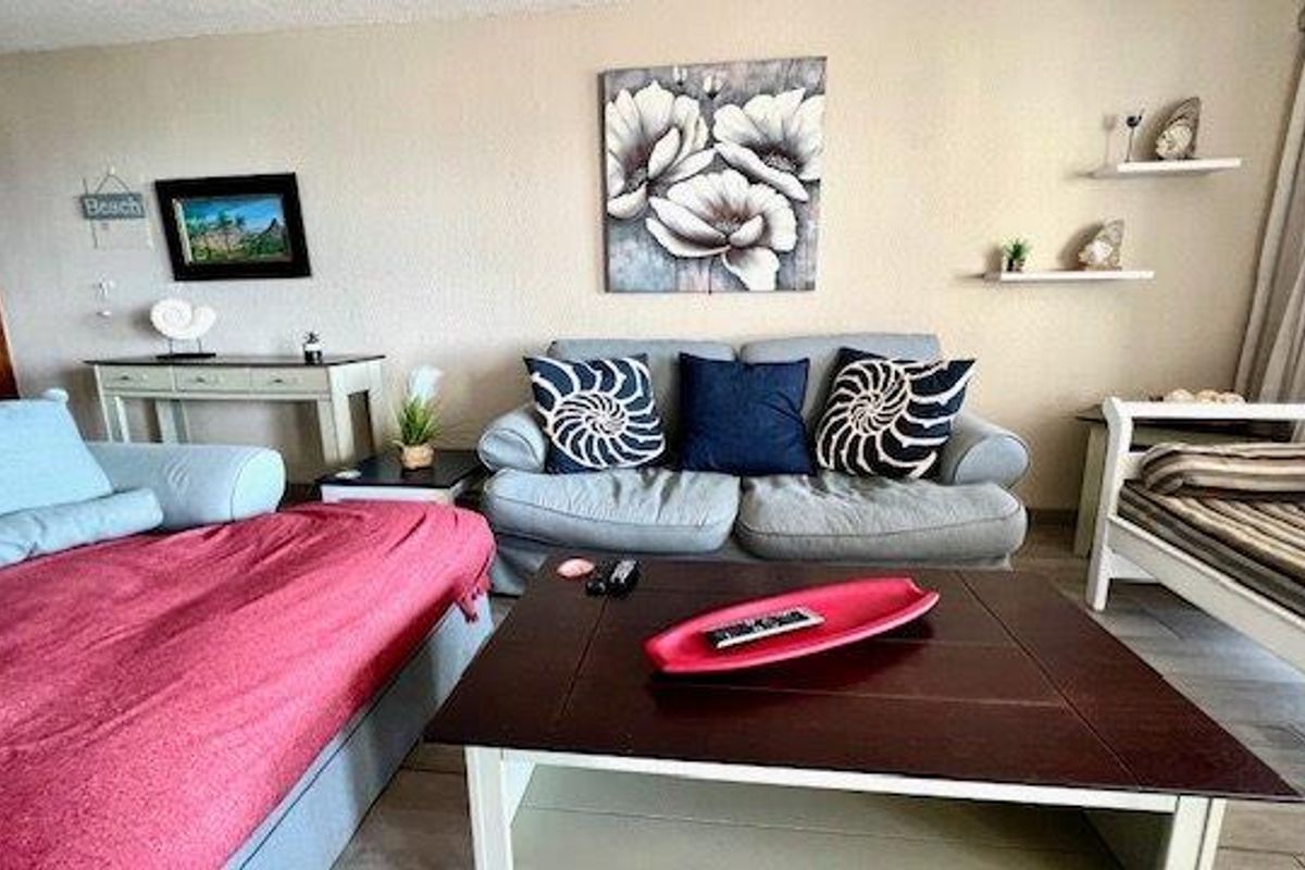 A comfortable living room area featuring tiled flooring and access to a balcony through a sliding door.