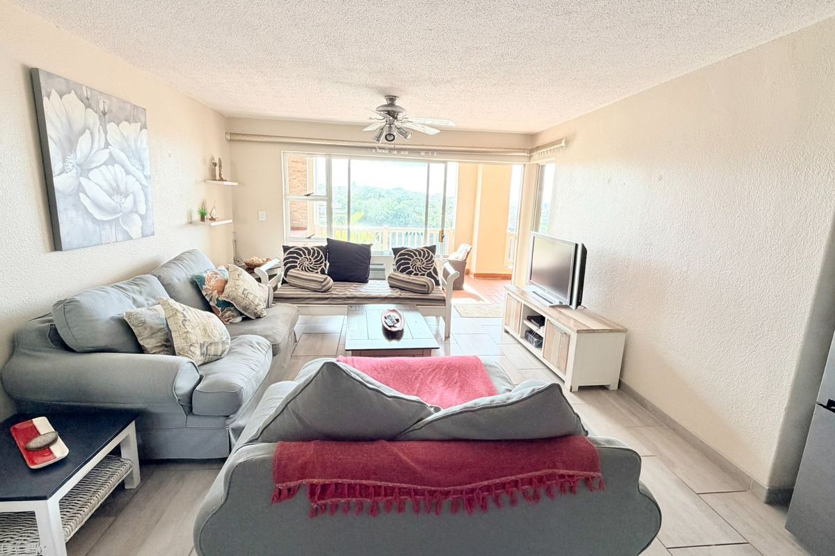 Spacious living room featuring tiled flooring, a ceiling fan, and large sliding glass doors that provide natural light and access to the balcony.