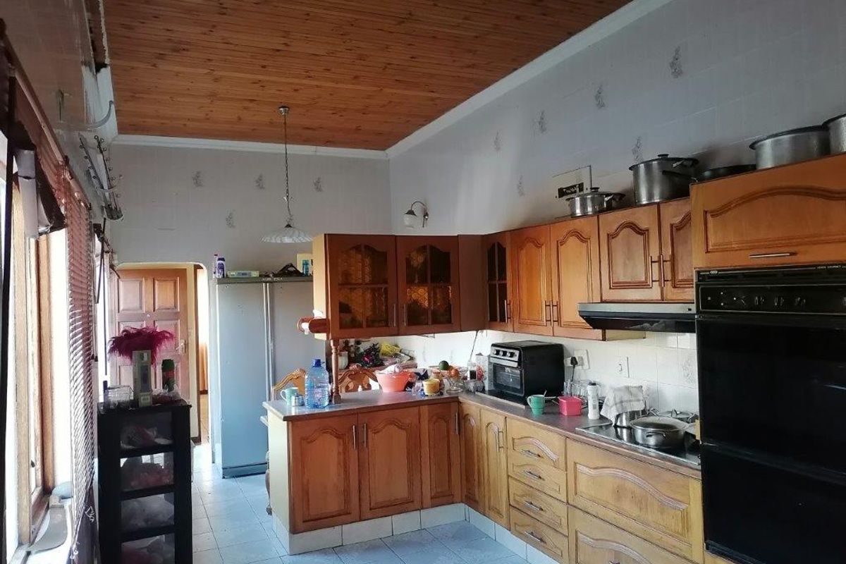 A functional kitchen featuring timber cabinetry, built-in oven, extractor fan, and tiled flooring with a timber-paneled ceiling.