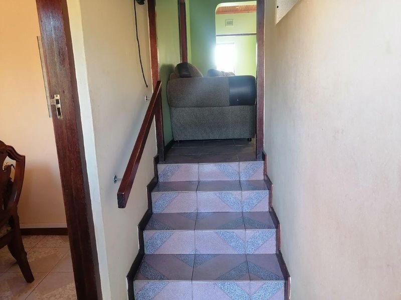A narrow interior staircase featuring tiled steps and a wooden handrail, providing access between levels of the home.