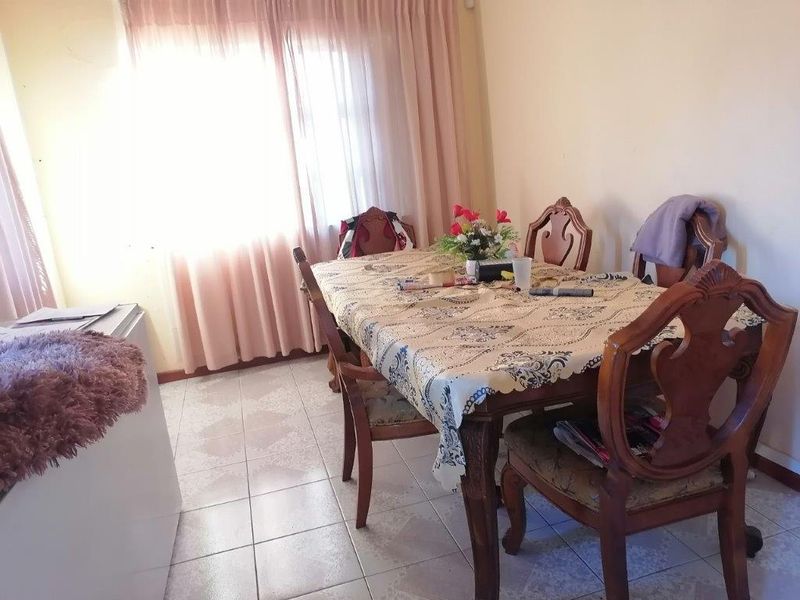 A dining area featuring tiled flooring and large windows with curtains, providing a functional space for meals.