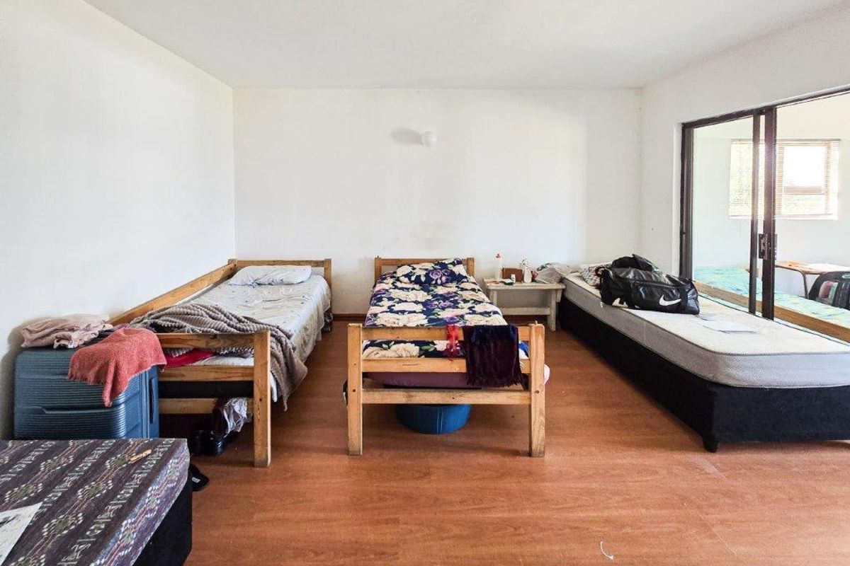 A spacious bedroom featuring laminate flooring and a large sliding glass door providing access to an outdoor area.