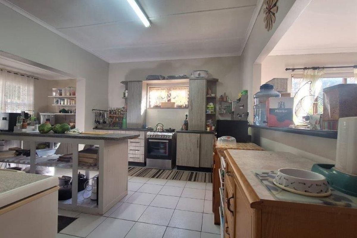 A functional kitchen featuring tiled flooring, built-in cabinetry, a central island, and a freestanding stove, offering a practical layout for daily meal preparation.