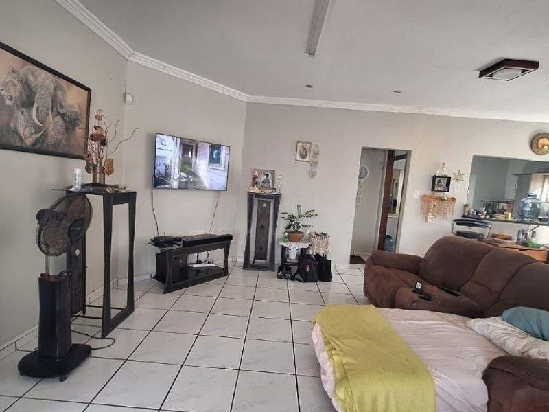 Open-plan living area featuring tiled flooring, coved cornicing, and a convenient pass-through window connecting to the kitchen space.