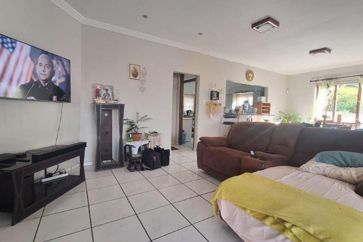 Spacious living room featuring neutral wall tones, ceramic tiled flooring, and direct access to the adjacent kitchen area.