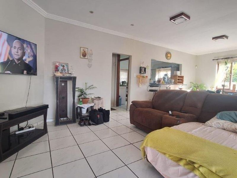 Spacious living room featuring neutral wall tones, ceramic tiled flooring, and direct access to the adjacent kitchen area.
