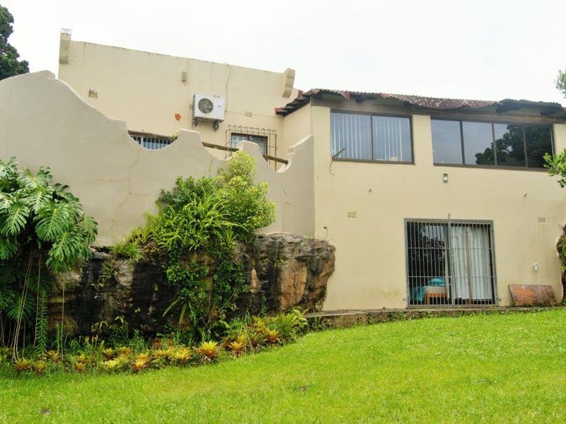 Rear view of the farm property featuring a natural rock foundation, sliding glass doors with security bars, and an exterior air conditioning unit.