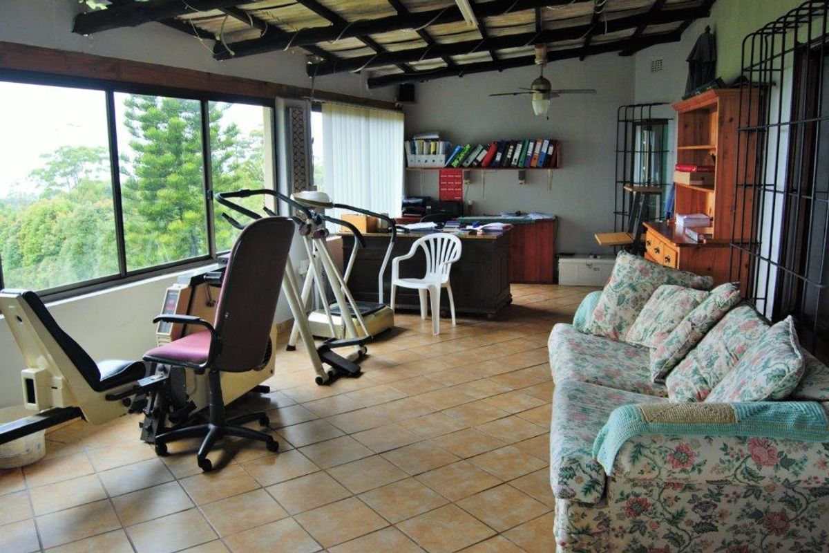 Spacious living area featuring exposed timber beams, ceramic tiled flooring, and large windows offering scenic views, currently utilized as a multi-purpose room.