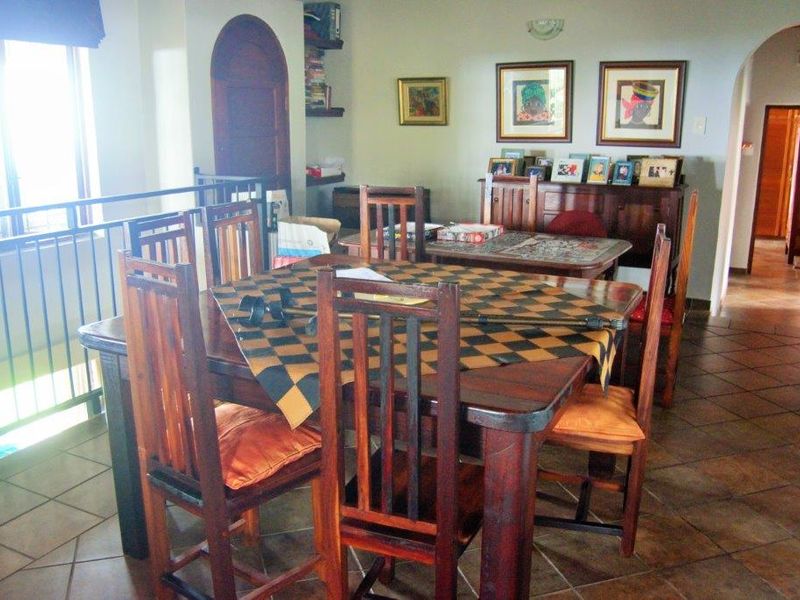 A dining area featuring tiled flooring, an arched doorway, and a metal balustrade overlooking an adjacent space.