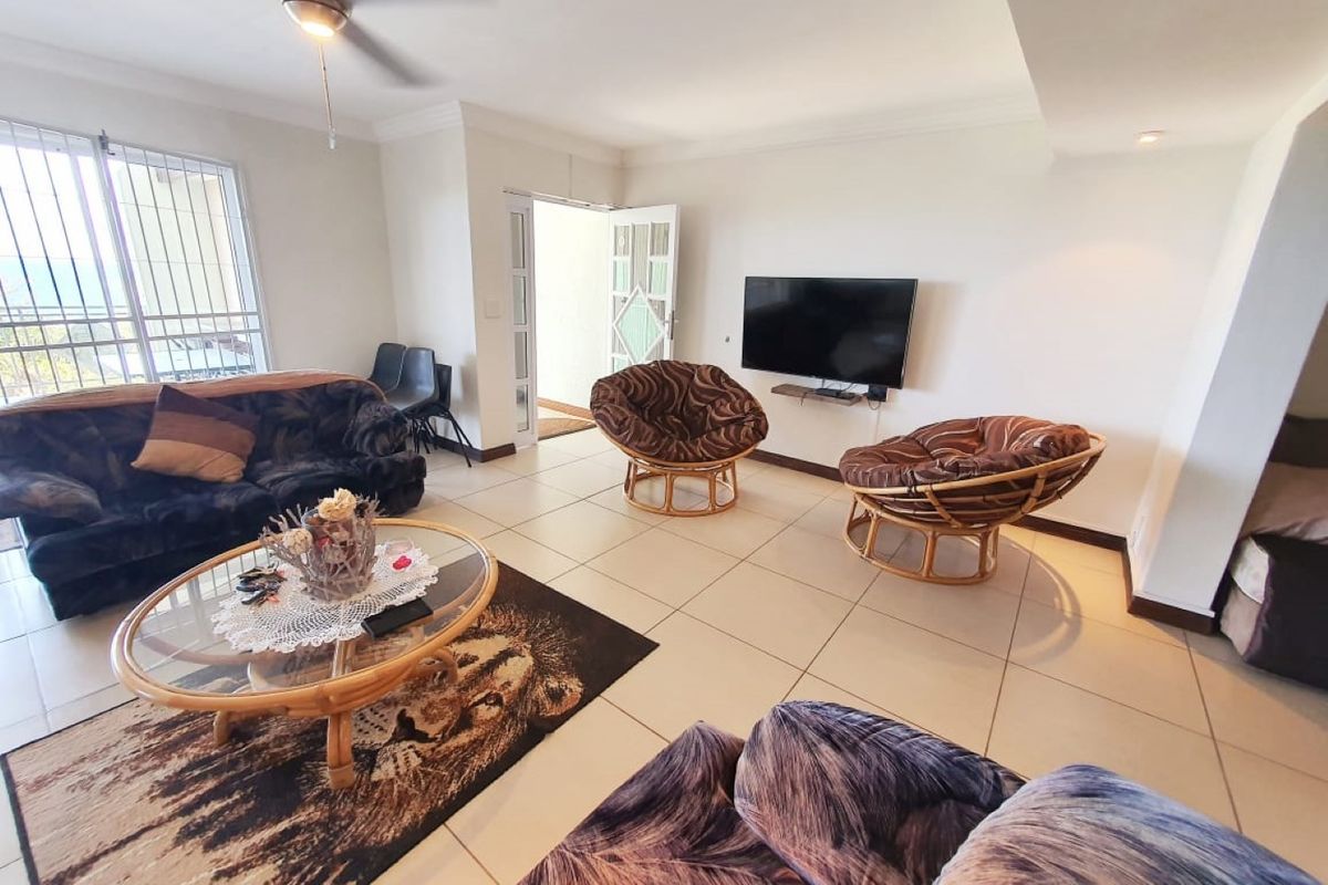 A bright living room featuring tiled flooring, a ceiling fan, and direct access to an outdoor area through a sliding glass door.