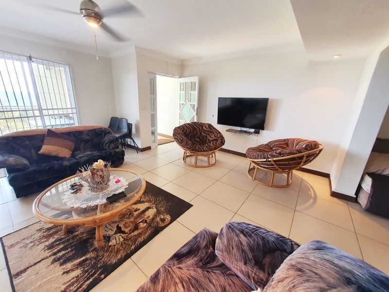 A bright living room featuring tiled flooring, a ceiling fan, and direct access to an outdoor area through a sliding glass door.