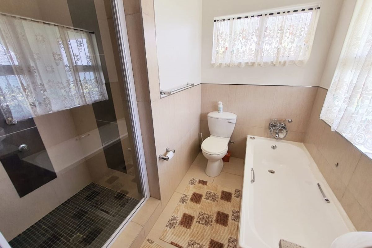 A functional bathroom featuring a separate shower enclosure, a bathtub, and a toilet with neutral wall and floor tiling.