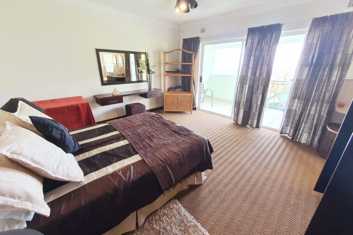 Spacious bedroom featuring carpet flooring, a ceiling fan, and sliding glass doors providing access to an outdoor balcony area.