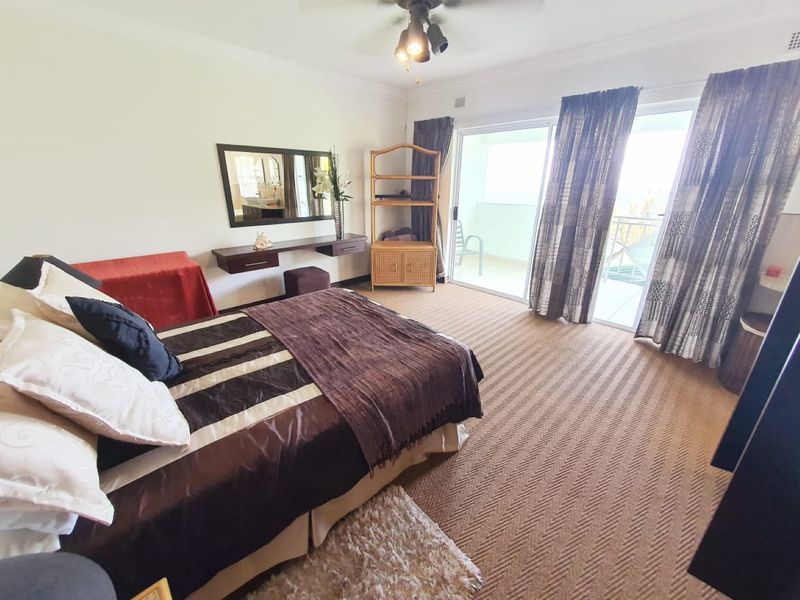 Spacious bedroom featuring carpet flooring, a ceiling fan, and sliding glass doors providing access to an outdoor balcony area.