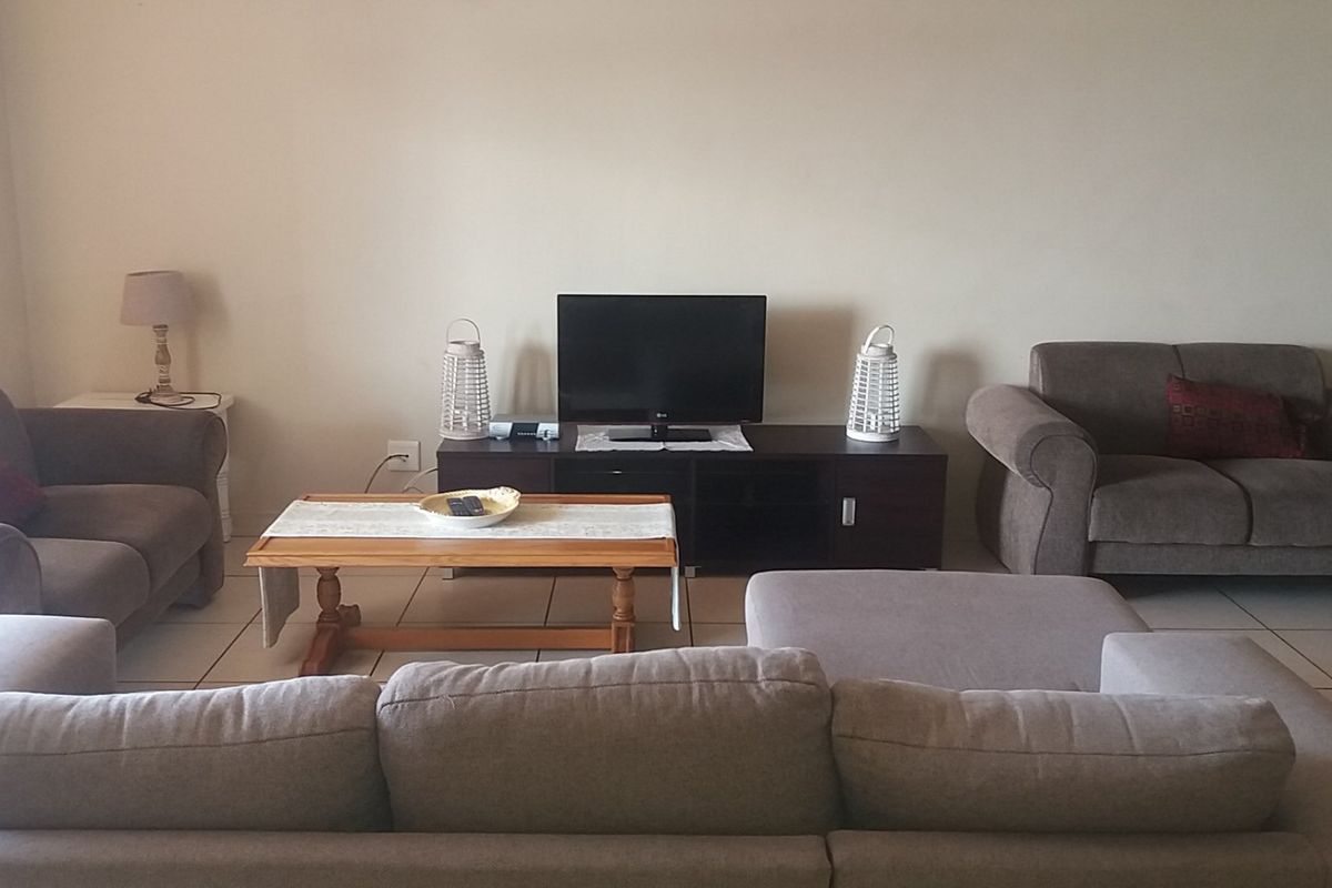 A comfortable living room featuring neutral tiled flooring and a spacious layout, providing a functional and inviting space for relaxation.
